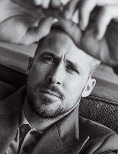 a man in a suit and tie sitting down with his hand on his head while looking at the camera