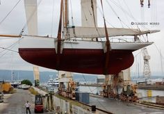 a large boat being lifted onto the side of a road by crane lifters and workers