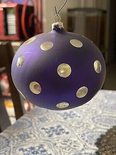 a purple and white polka dot ornament hanging from a string on a table