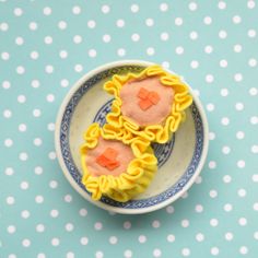 two small pastries sitting on top of a blue and white plate next to polka dot tablecloth