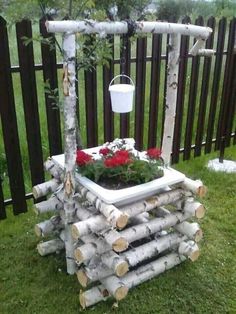 a planter made out of branches and logs with flowers in the middle on top