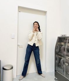 a woman standing in front of a door talking on a cell phone while holding her hand up to her face