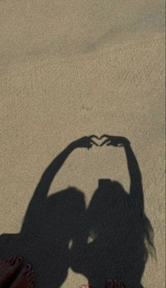 two people standing in the sand with their shadow