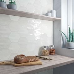 a wooden cutting board sitting on top of a counter next to a potted plant