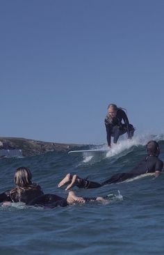 three people are in the water on surfboards