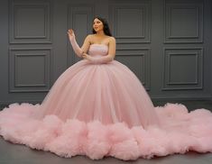 a woman in a pink ball gown standing on a pile of fluffy pink tulle