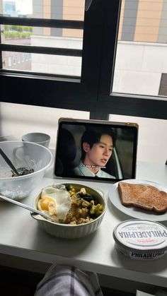 an open laptop computer sitting on top of a white desk next to a bowl of food