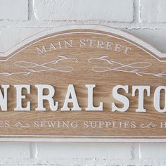 a wooden sign that says general store on the side of a brick wall with white lettering