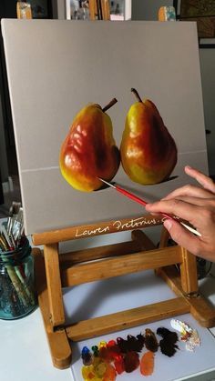 someone is painting two pears on an easel