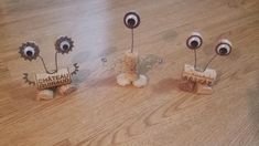 three wine corks with eyeballs on them sitting next to each other in front of a wooden table