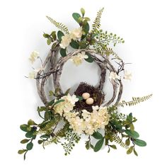 a bird's nest with flowers and greenery on a white background, surrounded by branches