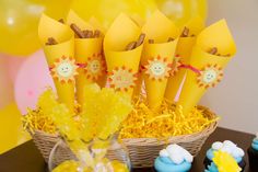 a table topped with cupcakes covered in yellow frosting and sunburst decorations