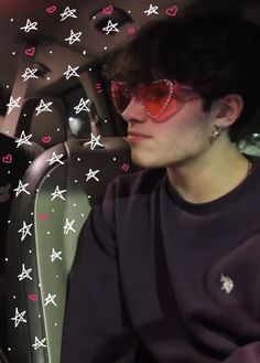 a young man wearing sunglasses sitting in the back seat of a car with hearts and stars on it