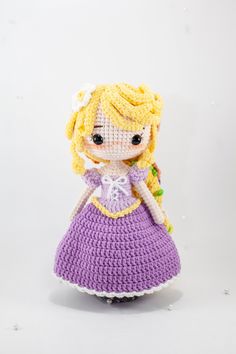 a crocheted doll is wearing a purple dress