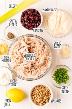 ingredients to make chicken salad laid out in bowls on a white surface with lemons, celery, mayonnaise, cran and other ingredients