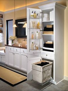 a bathroom with white cabinets and shelves filled with personal care items, including a laundry basket