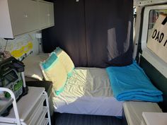 a bed in the back of a truck with a blue and yellow blanket on it