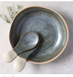 a ceramic bowl with spoons and sprig of rosemary on the side, top view