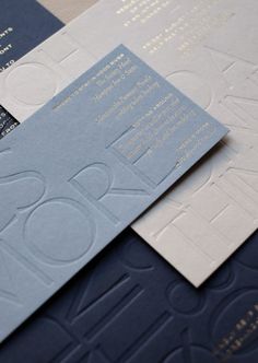 some blue and white business cards on top of each other with gold foil lettering in the middle