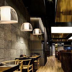 the interior of a restaurant with wooden tables, chairs and lamps hanging from the ceiling