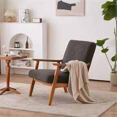 a chair with a blanket on it in a living room next to a potted plant