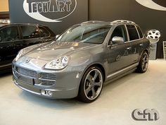 two cars are on display in a showroom, one is silver and the other is black