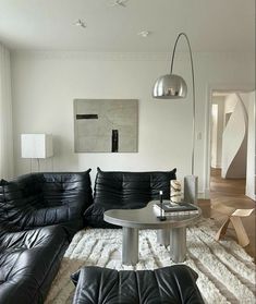 a living room with black leather couches and a round coffee table in the middle