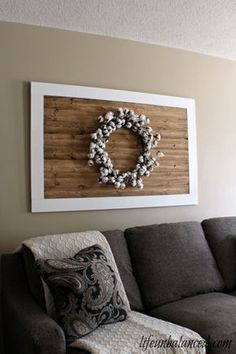 a living room with a gray couch and white wreath on the wall