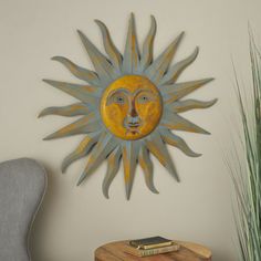 a metal sun face mounted to the side of a wall next to a table and chair