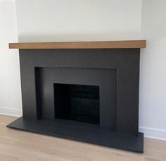 an empty fireplace in a white room with wood flooring