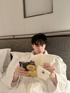 a person laying in bed reading a book and looking at the camera with an expression on their face