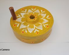 a yellow and white painted object with a wooden stick sticking out of it's center