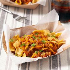 two baskets filled with nachos sitting on top of a table next to a fork