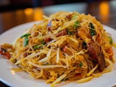 a close up of a plate of food with noodles and meats on the side