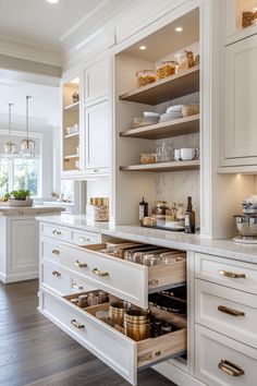 a kitchen with white cabinets and open drawers