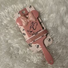 a cell phone case with a pink bow and name tag on it, sitting on a white carpet