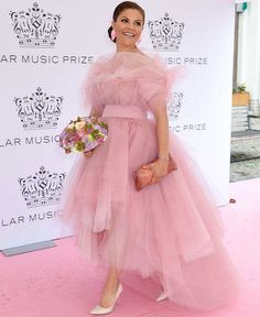 a woman in a pink dress standing on a pink carpet