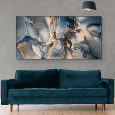 a blue couch sitting in front of a painting on the wall