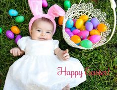 a baby in a white dress and bunny ears next to an easter basket filled with eggs