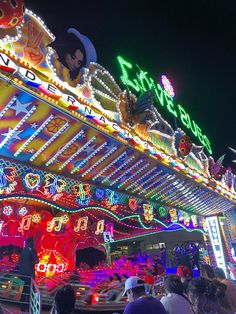 people are standing in front of a brightly lit building at night with lights all around it