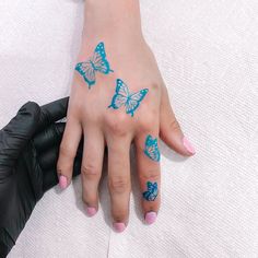 a woman's hand with blue butterflies painted on her left wrist and right hand