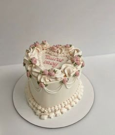 a heart shaped cake with roses and pearls around the edges on a white platter