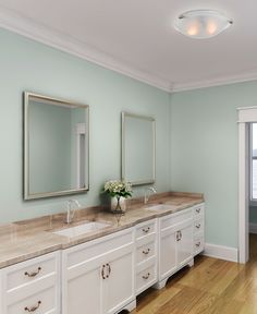 a large bathroom with two sinks and mirrors on the wall, along with hardwood flooring