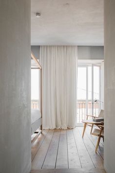 an open room with white curtains and wooden floors