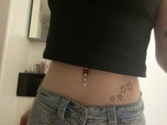 a woman's stomach with small stars on the side and a cross tattoo on it