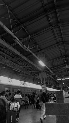 black and white photograph of people walking around in a train station