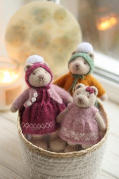 three teddy bears are sitting in a basket on the window sill next to a candle