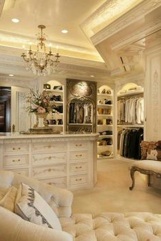 an elegant closet with white furniture and chandelier hanging from the ceiling in front of it