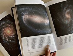 an open book with two pictures of the same spiral galaxy in it's pages