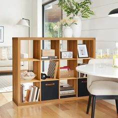 a room with a table, chairs and bookshelf filled with various items in it